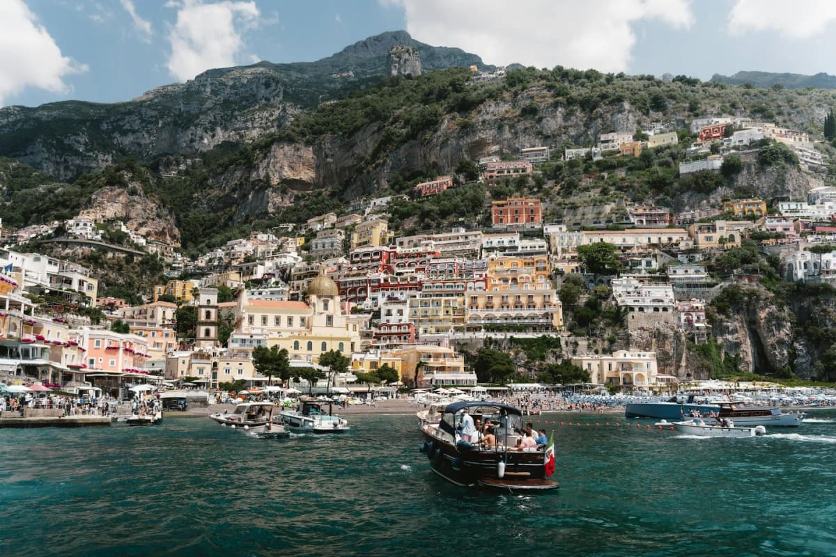 Boats arriving at Positano, with the town's houses climbing the hillside behind the beach