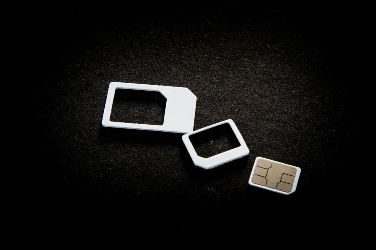 Three sizes of physical SIM card and adaptors on a dark surface