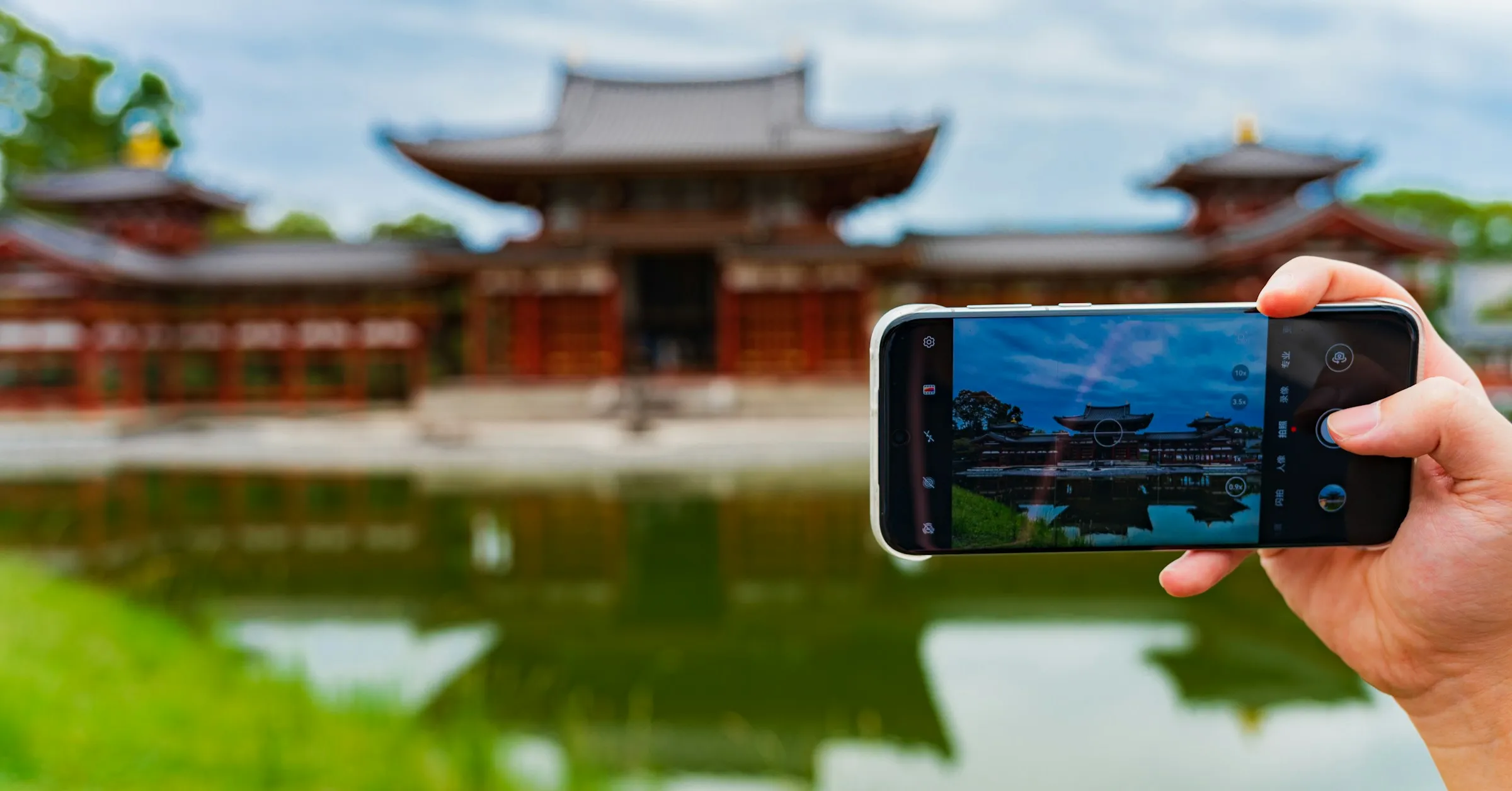 Best eSIM for Japan: a traveller photographing a temple and its reflecting pond with a smartphone