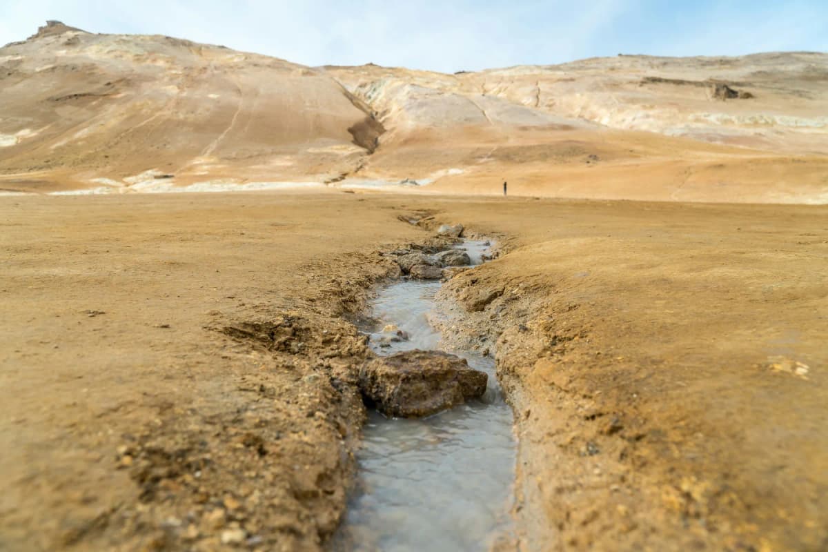 Best places to visit in Iceland: a milky geothermal stream running through the ochre landscape at Hverir near Lake Mývatn