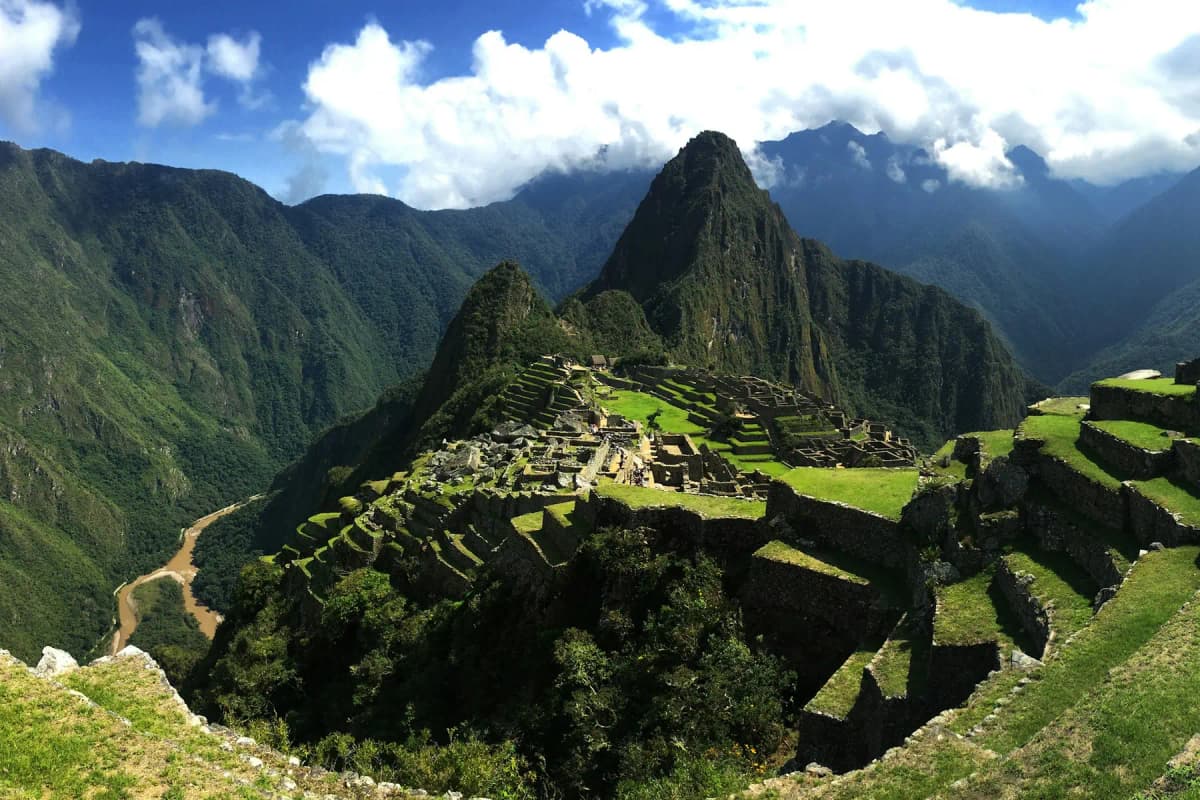 The terraces and ruins of Machu Picchu under a blue sky with a few clouds