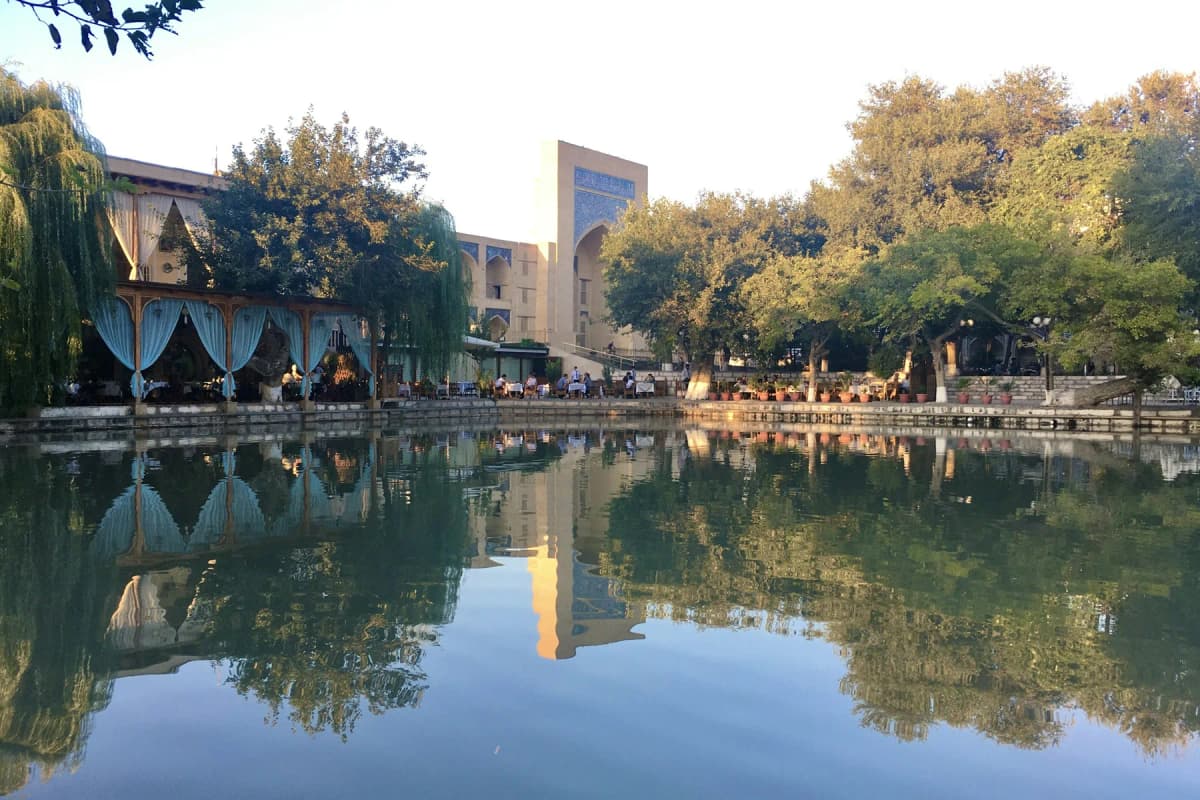 Lyabi-Hauz pool in Bukhara, with a madrasa and trees reflected in the water