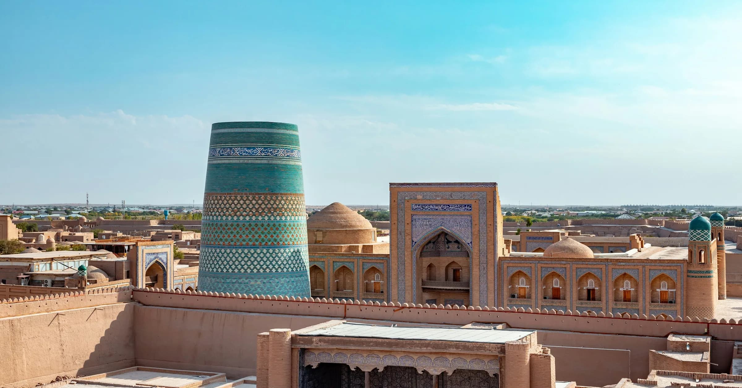 Bukhara to Khiva: the turquoise-tiled Kalta Minor minaret rising above the mud-brick rooftops of Itchan Kala in Khiva