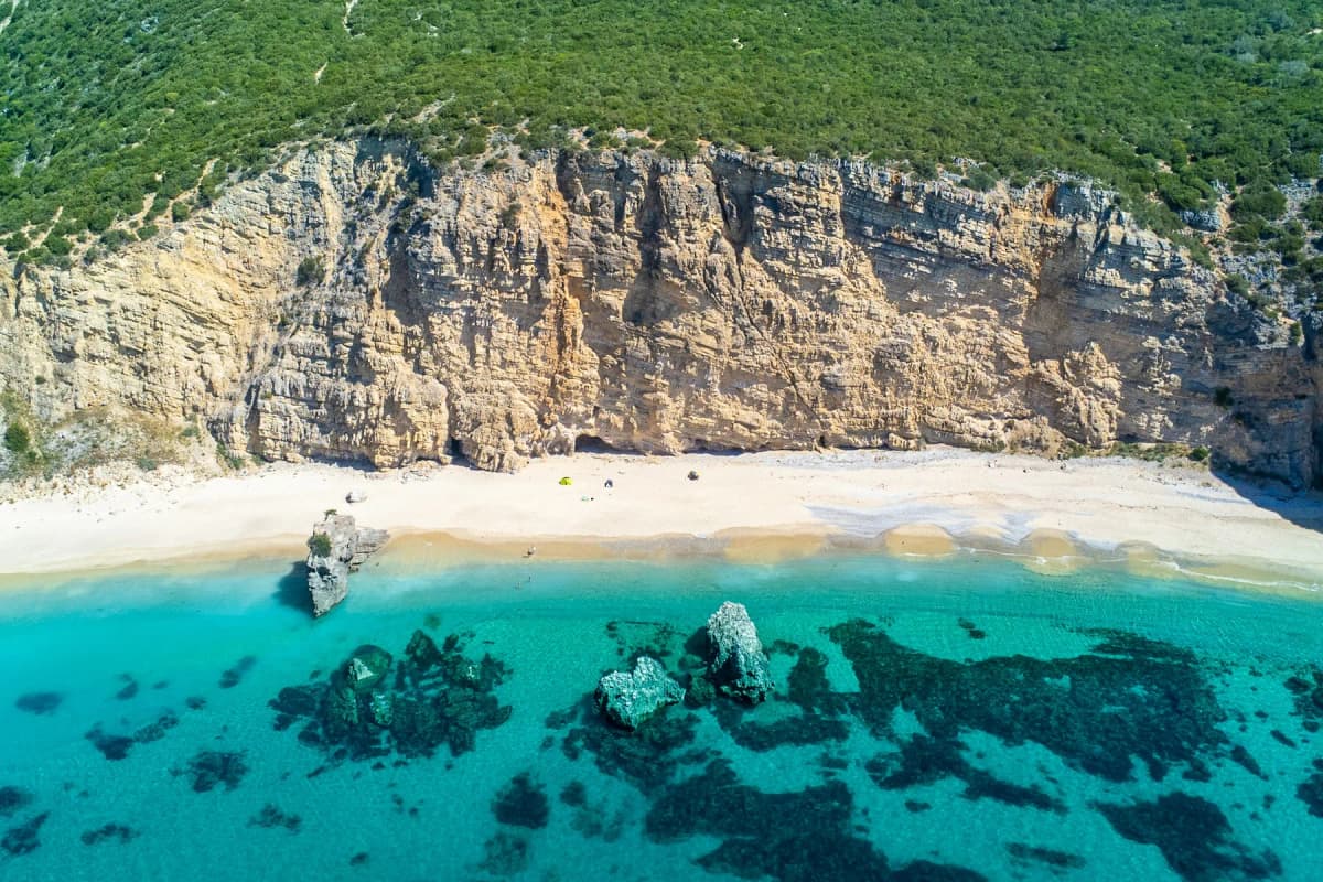 A sandy cove under white limestone cliffs on the Arrábida coast south of Lisbon