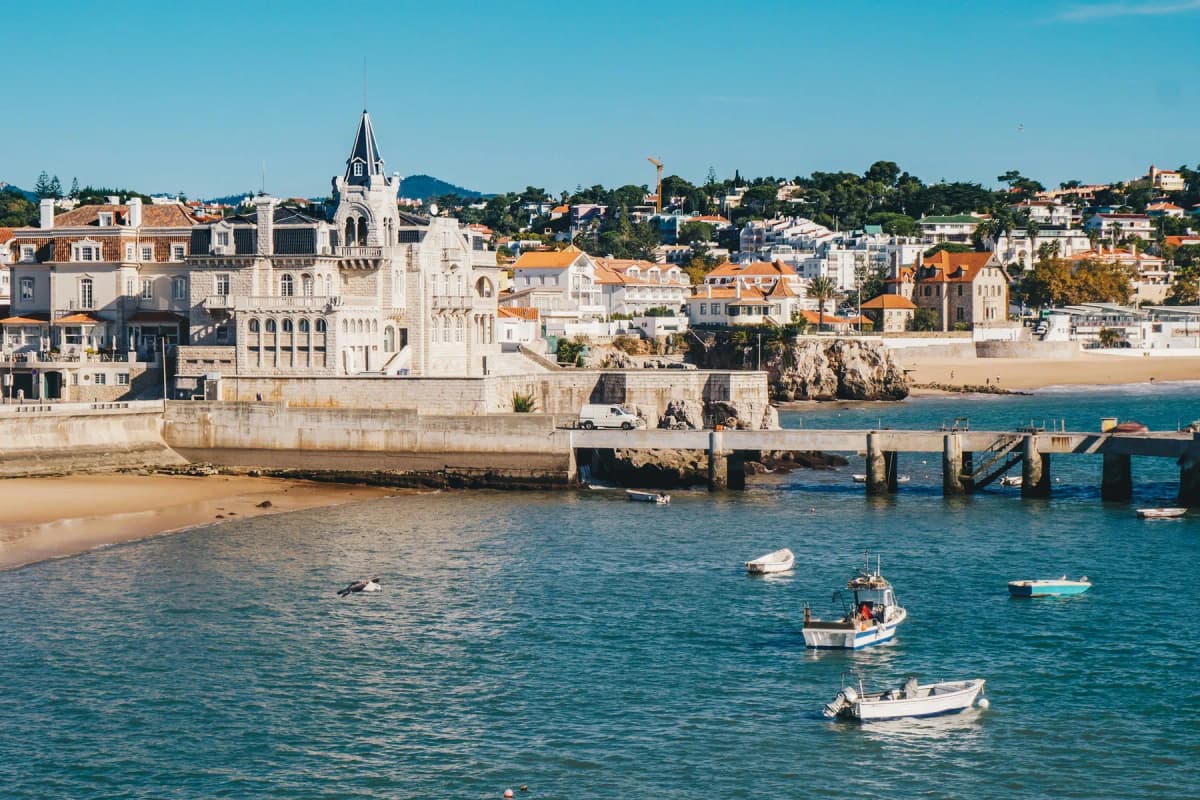 The seafront of Cascais with fishing boats in the bay and the old town behind