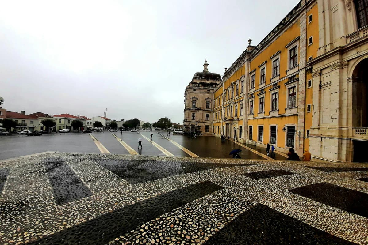 The long facade of the National Palace of Mafra beside a patterned cobbled square