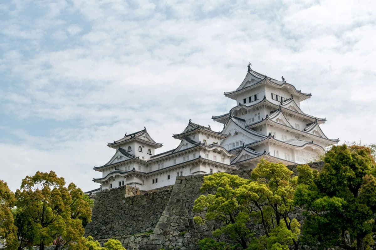 The white towers of Himeji Castle rising above trees and stone walls