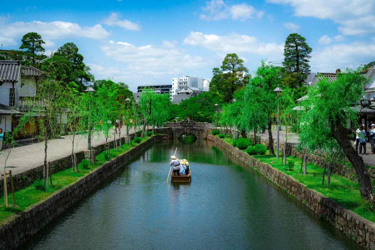 A boatman punting along the willow-lined canal in Kurashiki