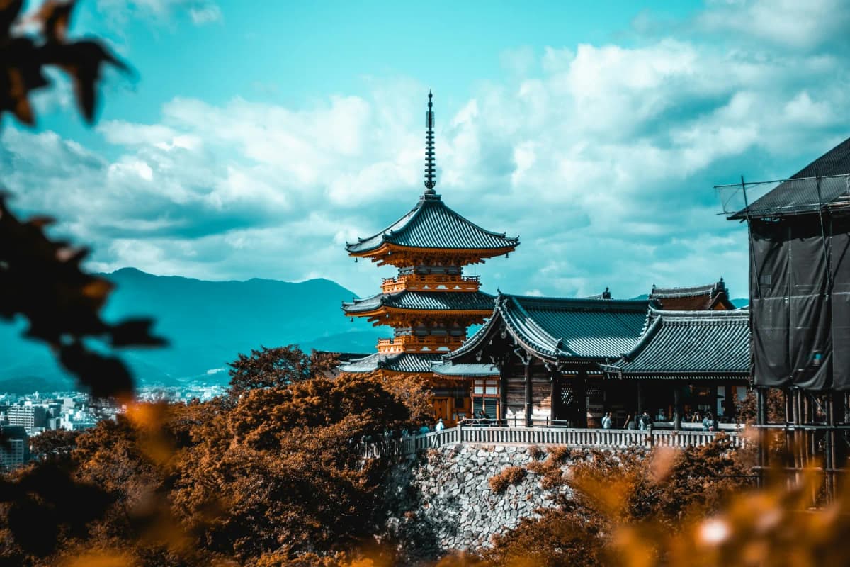 A vermilion pagoda surrounded by autumn leaves at a temple in Kyoto