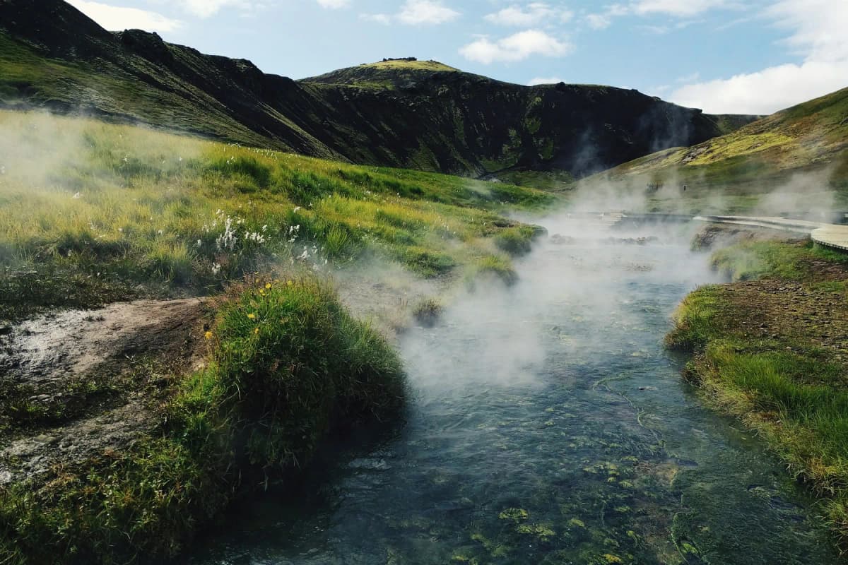 Day trips from Reykjavik: steam rising from the warm river in the green Reykjadalur valley near Hveragerði