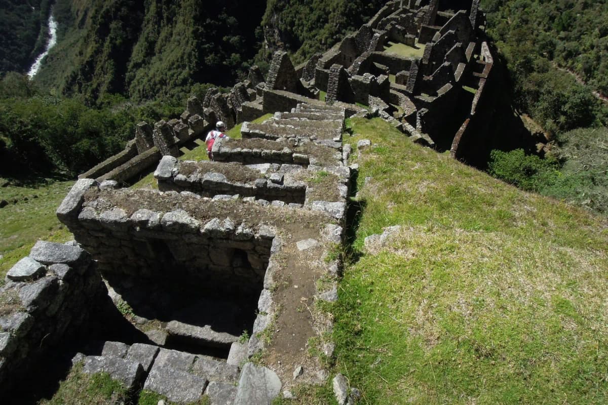 Hikers crossing an Inca stone causeway beside ruins on the Inca Trail