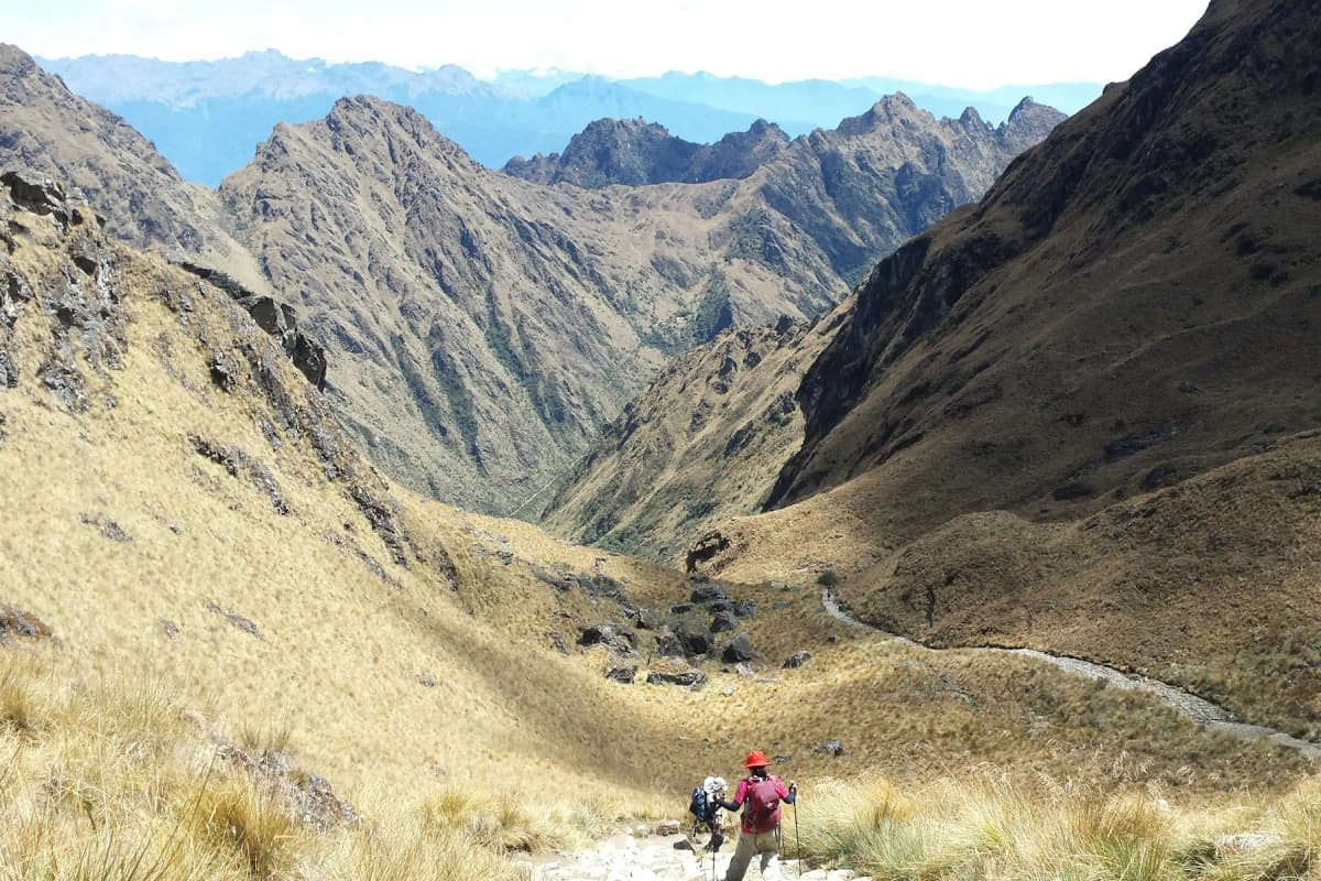 Two hikers on a dry, golden trail in a high valley on the Inca Trail