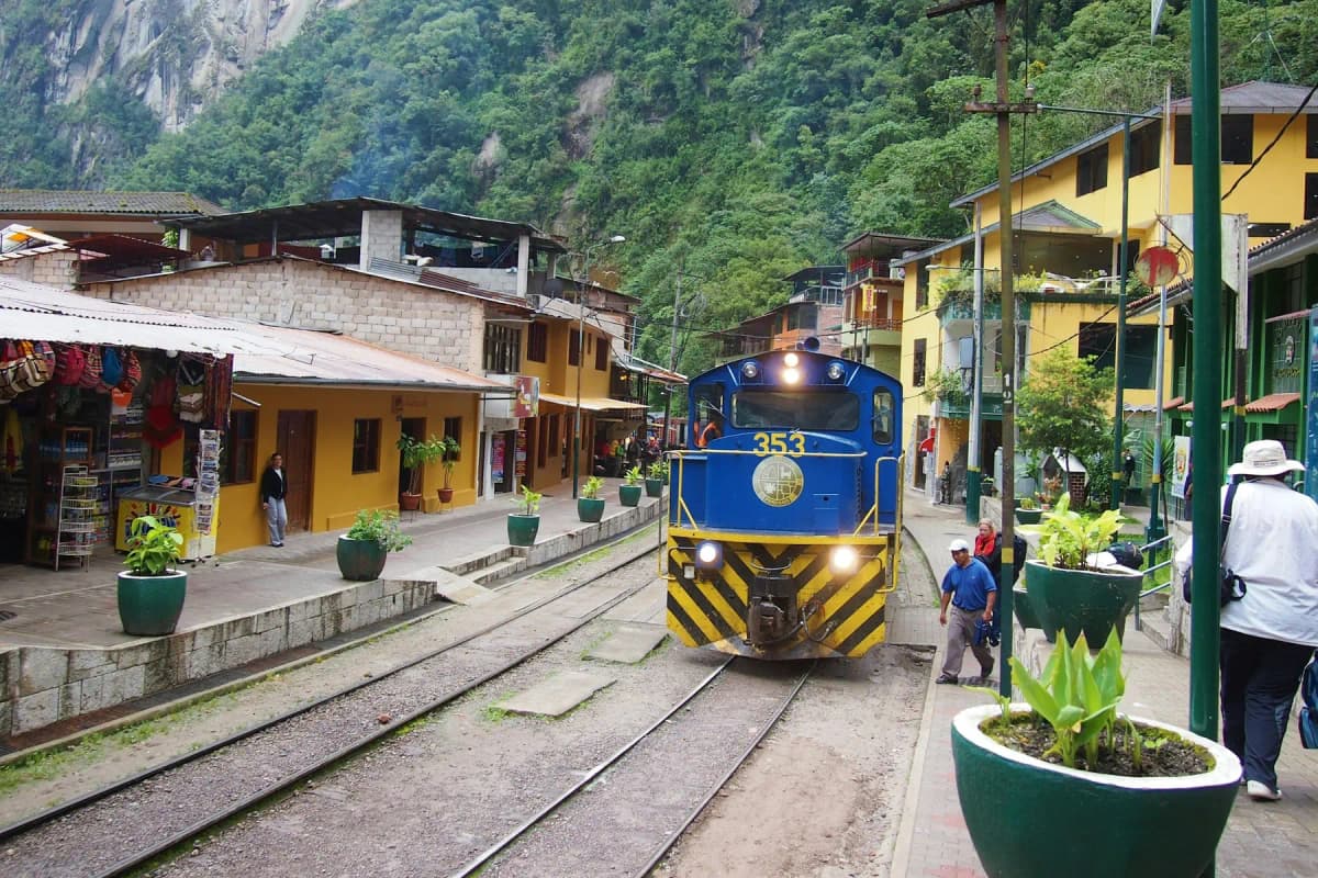 A blue train at the platform in Aguas Calientes, with shops and cafés beside the tracks