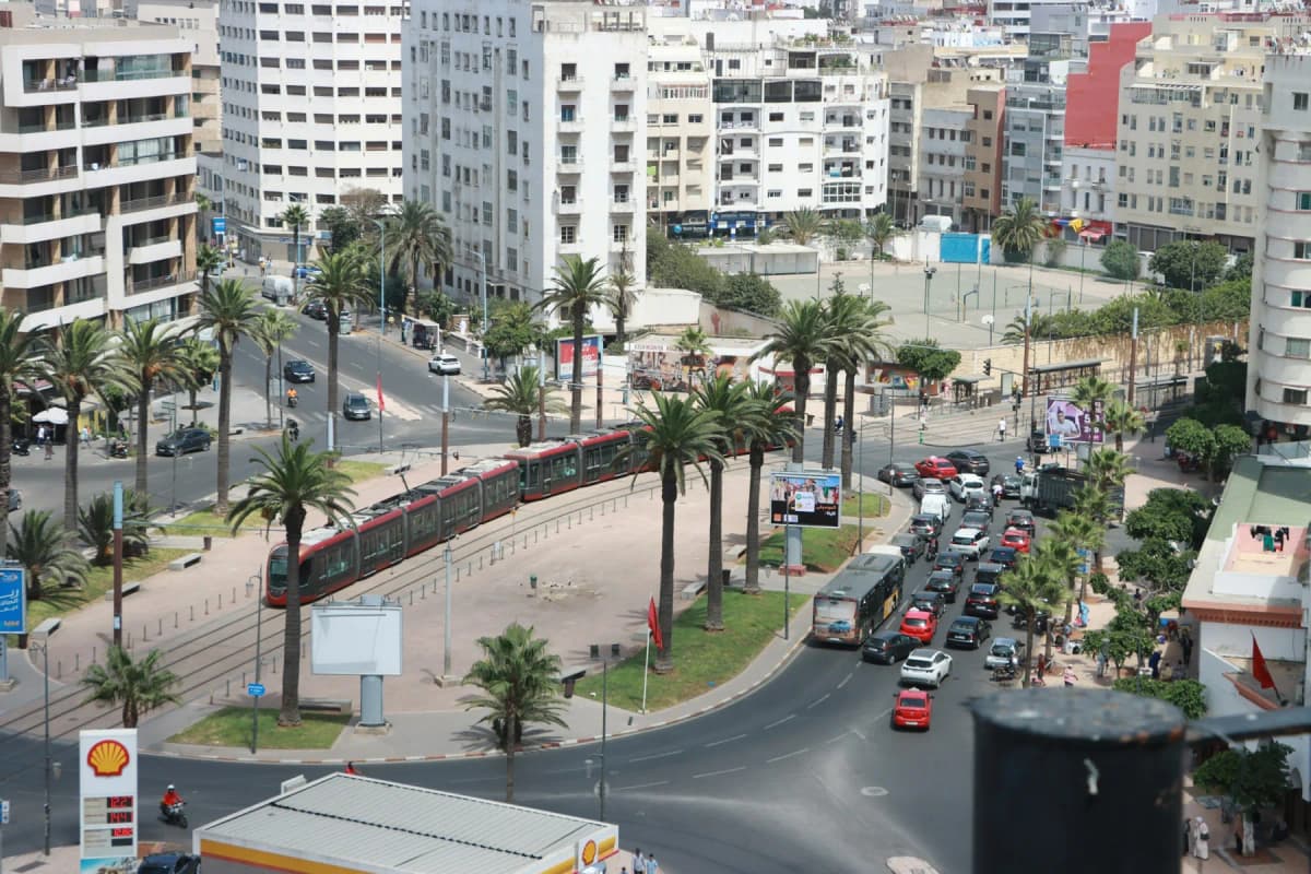 A wide boulevard lined with palm trees, apartment blocks and a red tram in the centre of Casablanca