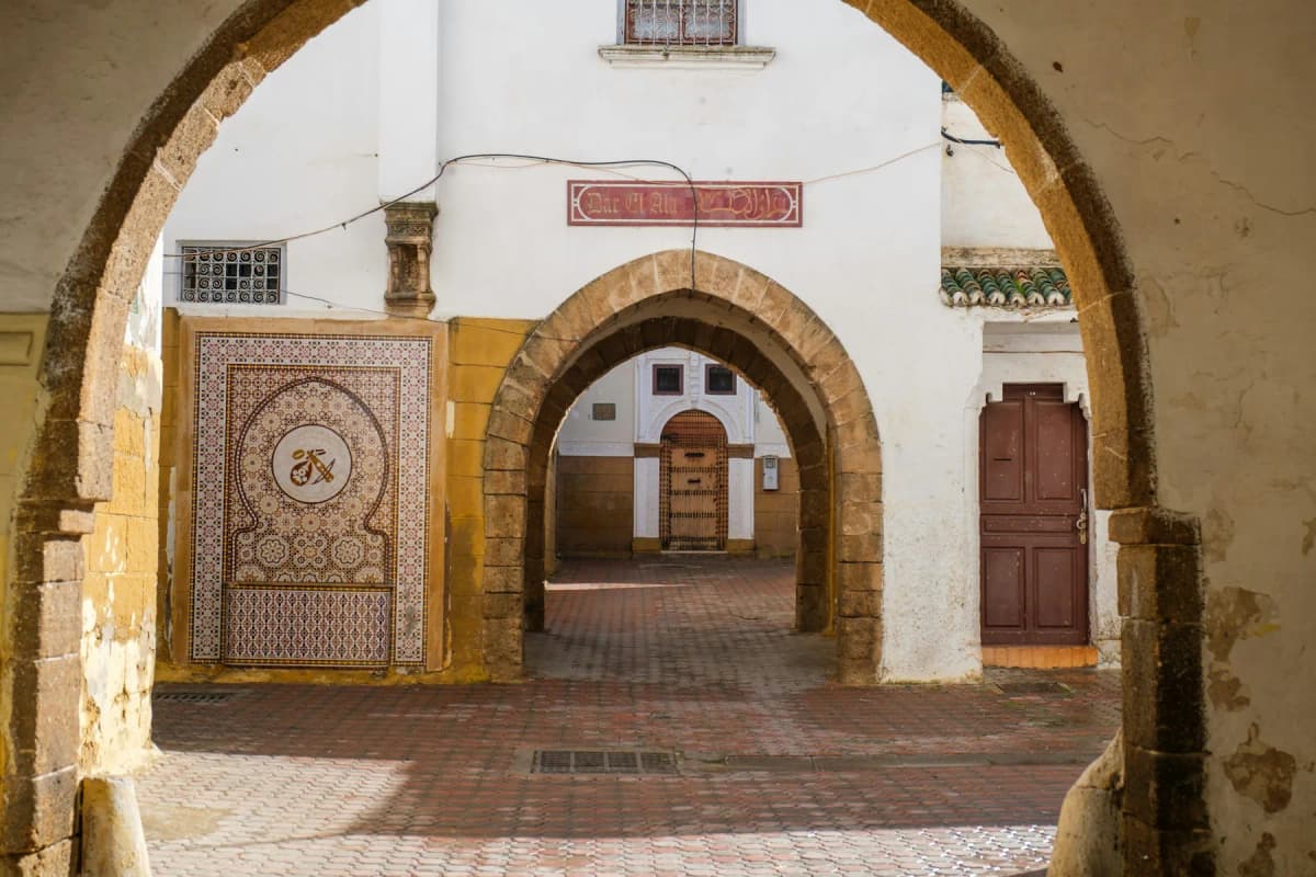 A tiled fountain and whitewashed horseshoe arches in a quiet lane of an old quarter in Casablanca