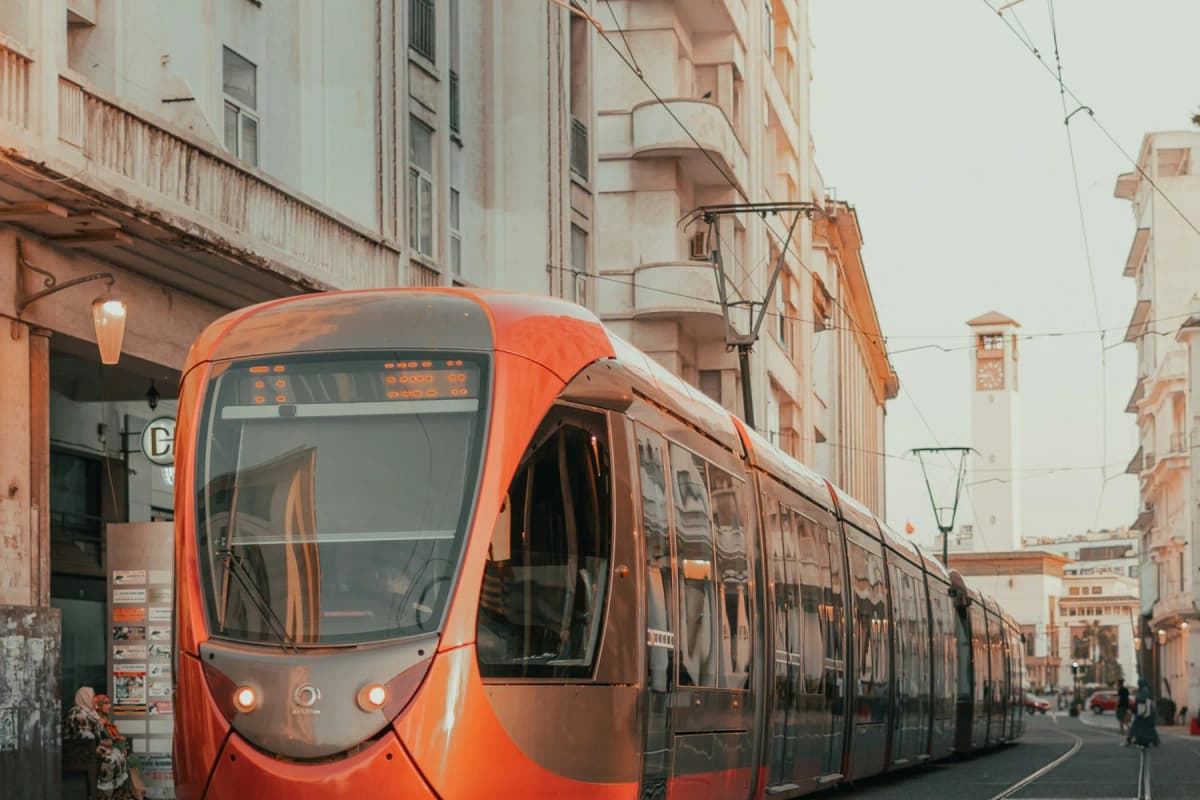 An orange Casablanca tram passing Art Deco buildings in the city centre at sunset