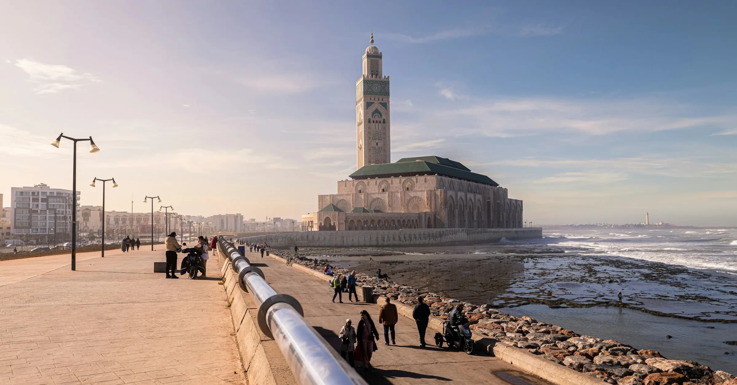Is Casablanca safe: people walking along the seafront promenade towards the Hassan II Mosque in Casablanca