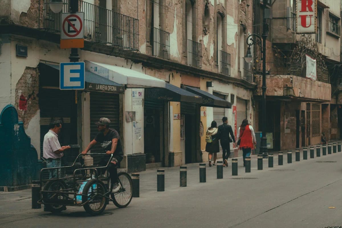 A cyclist and pedestrians on a narrow street in Mexico City's historic centre
