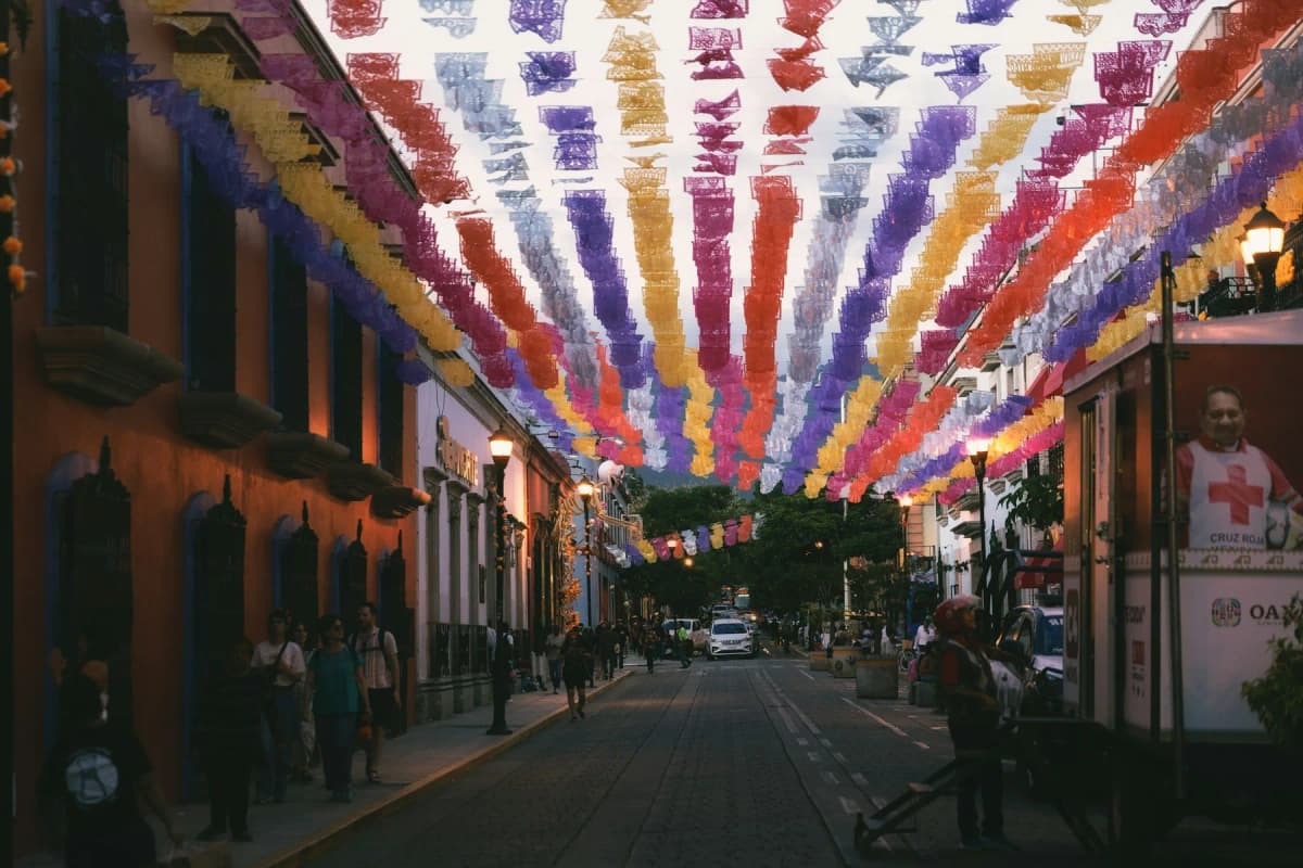A street in Oaxaca's historic centre at dusk, strung with papel picado bunting