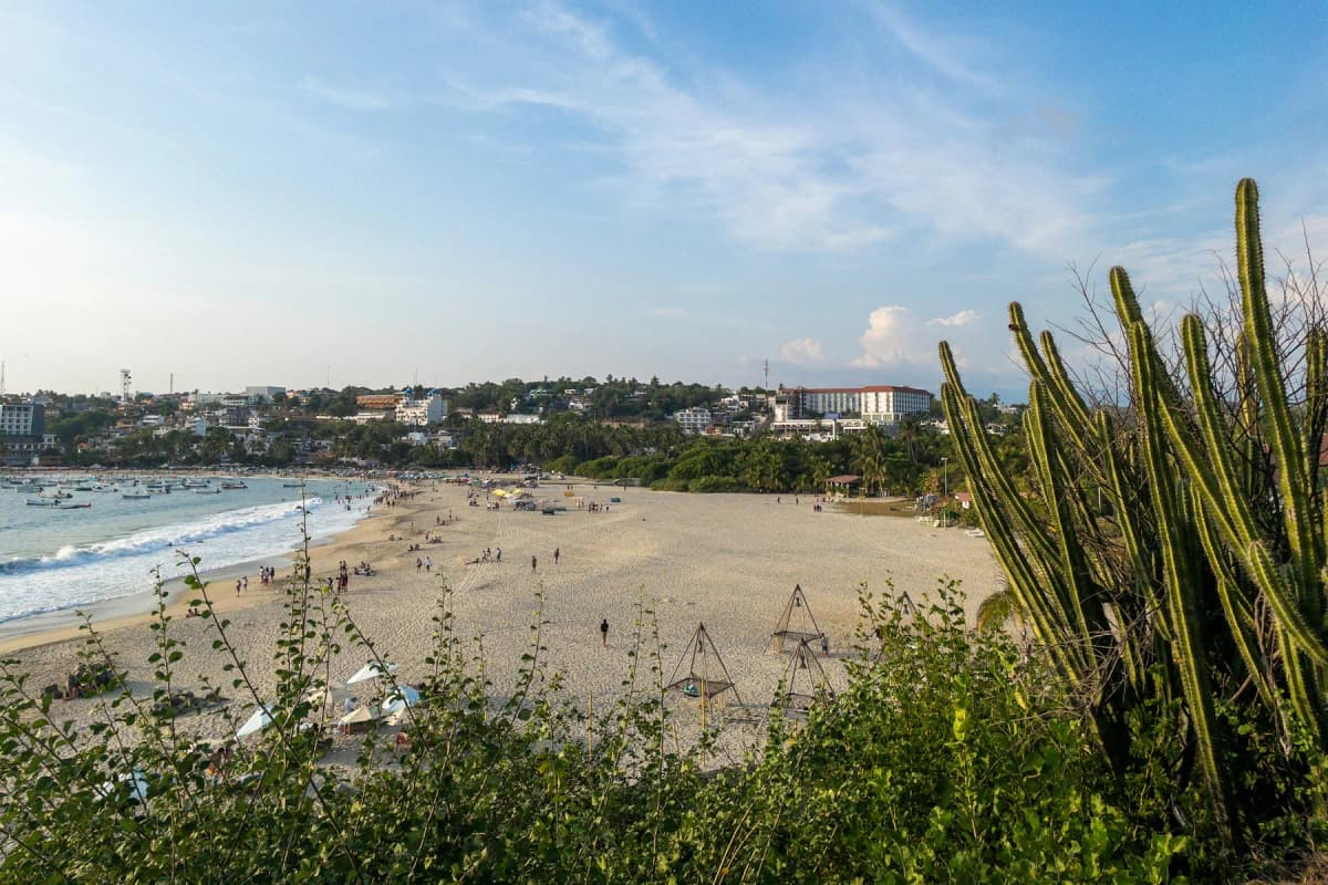 People on the beach at Puerto Escondido, with the town behind