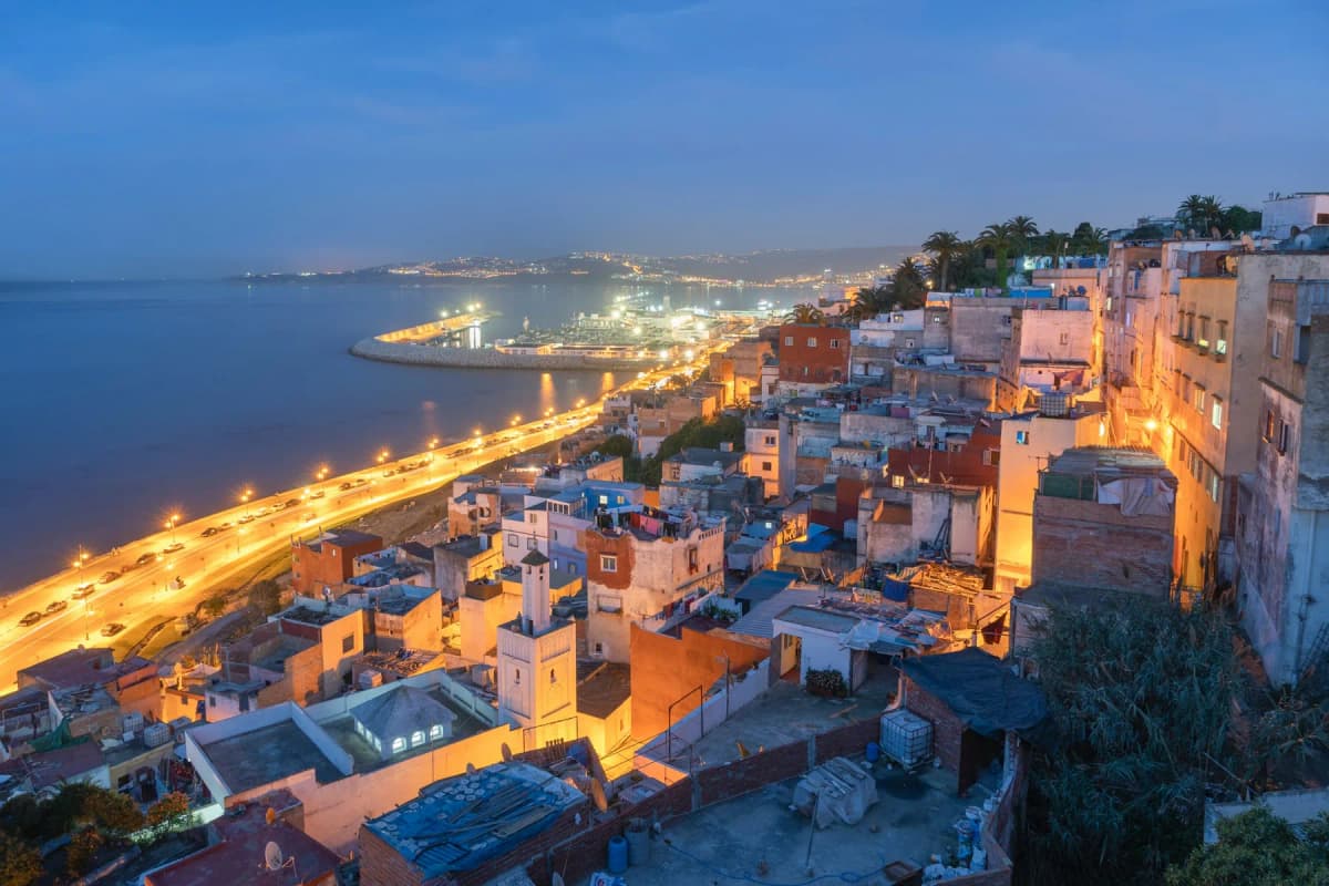 Tangier at night, with the lit corniche road curving along the bay below the houses of the medina