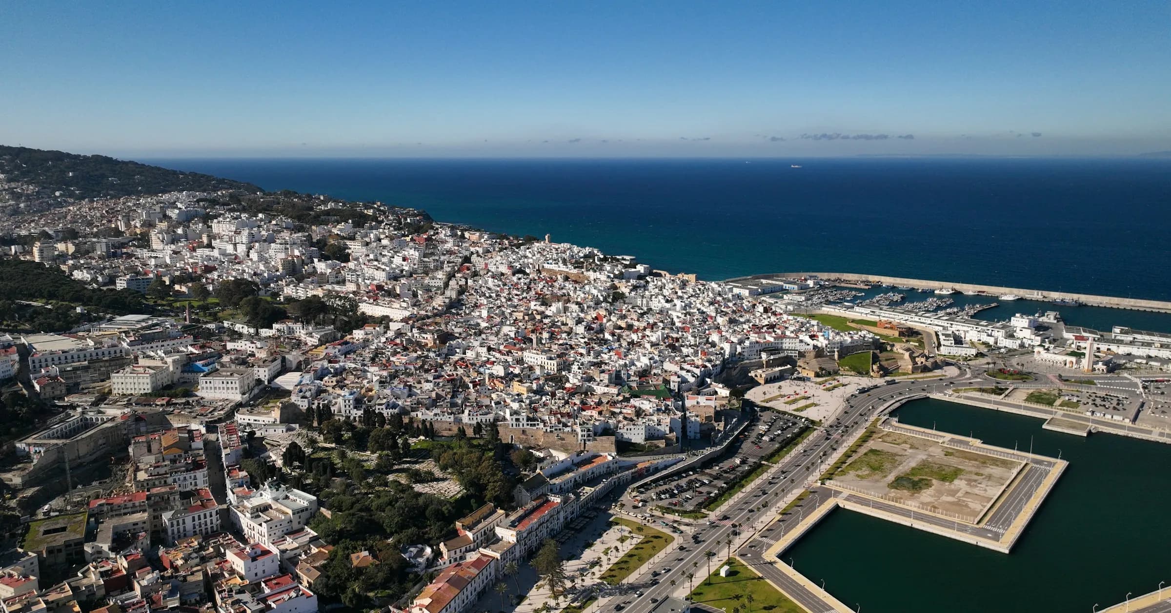 Is Tangier safe: aerial view of the white medina of Tangier, the marina and the Strait of Gibraltar on a clear day