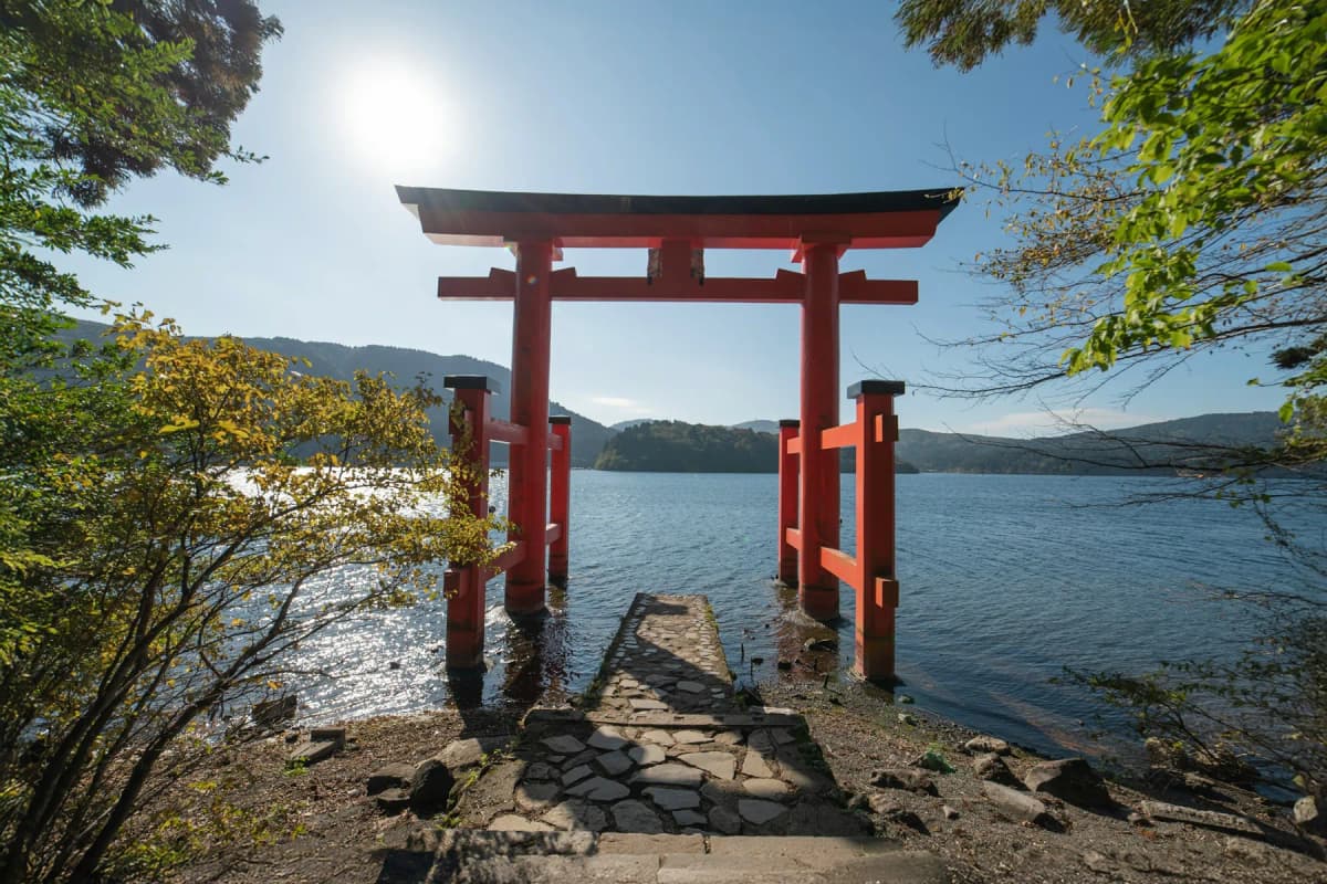 A red torii gate standing at the edge of Lake Ashi in Hakone