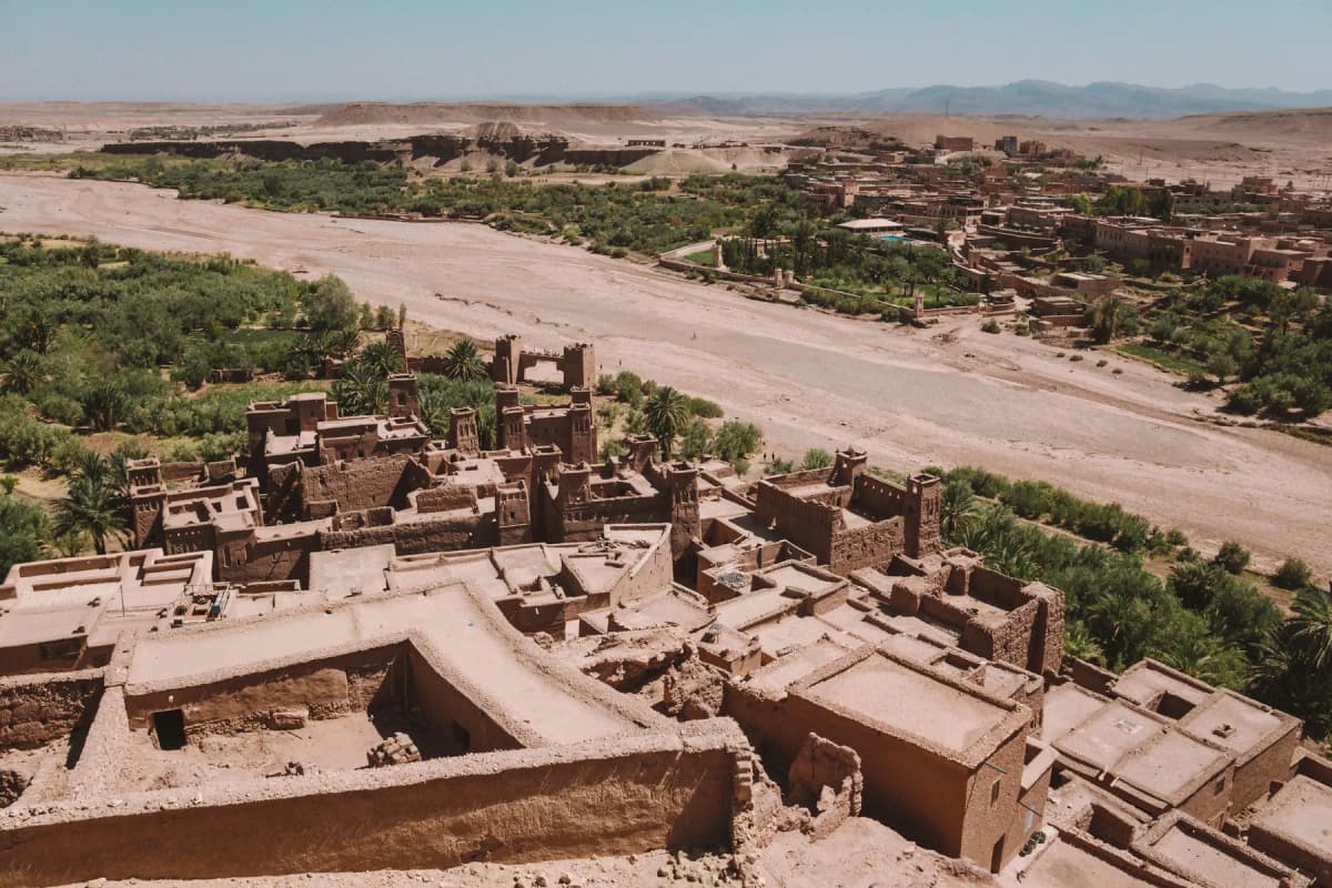 The mud-brick village of Aït Benhaddou beside a dry riverbed and palm groves in southern Morocco