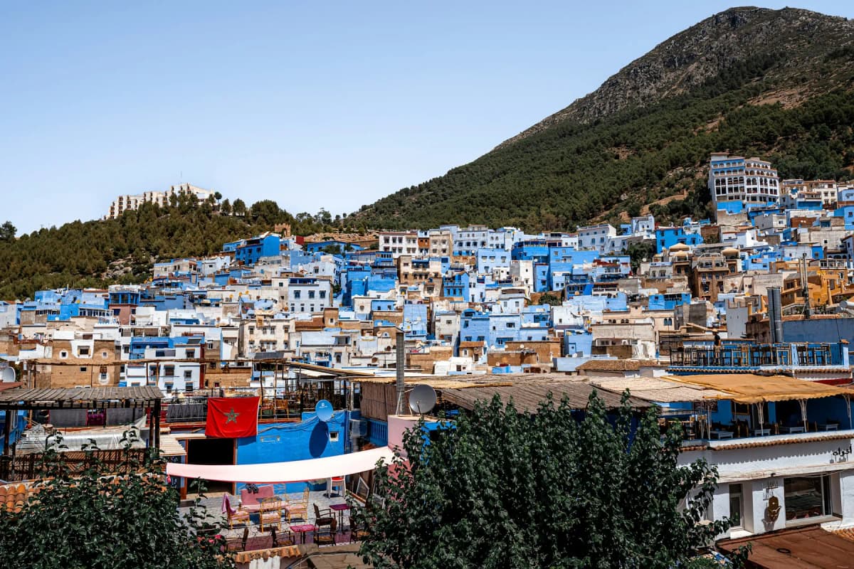 The blue and white houses of Chefchaouen spread across a hillside below the Rif mountains