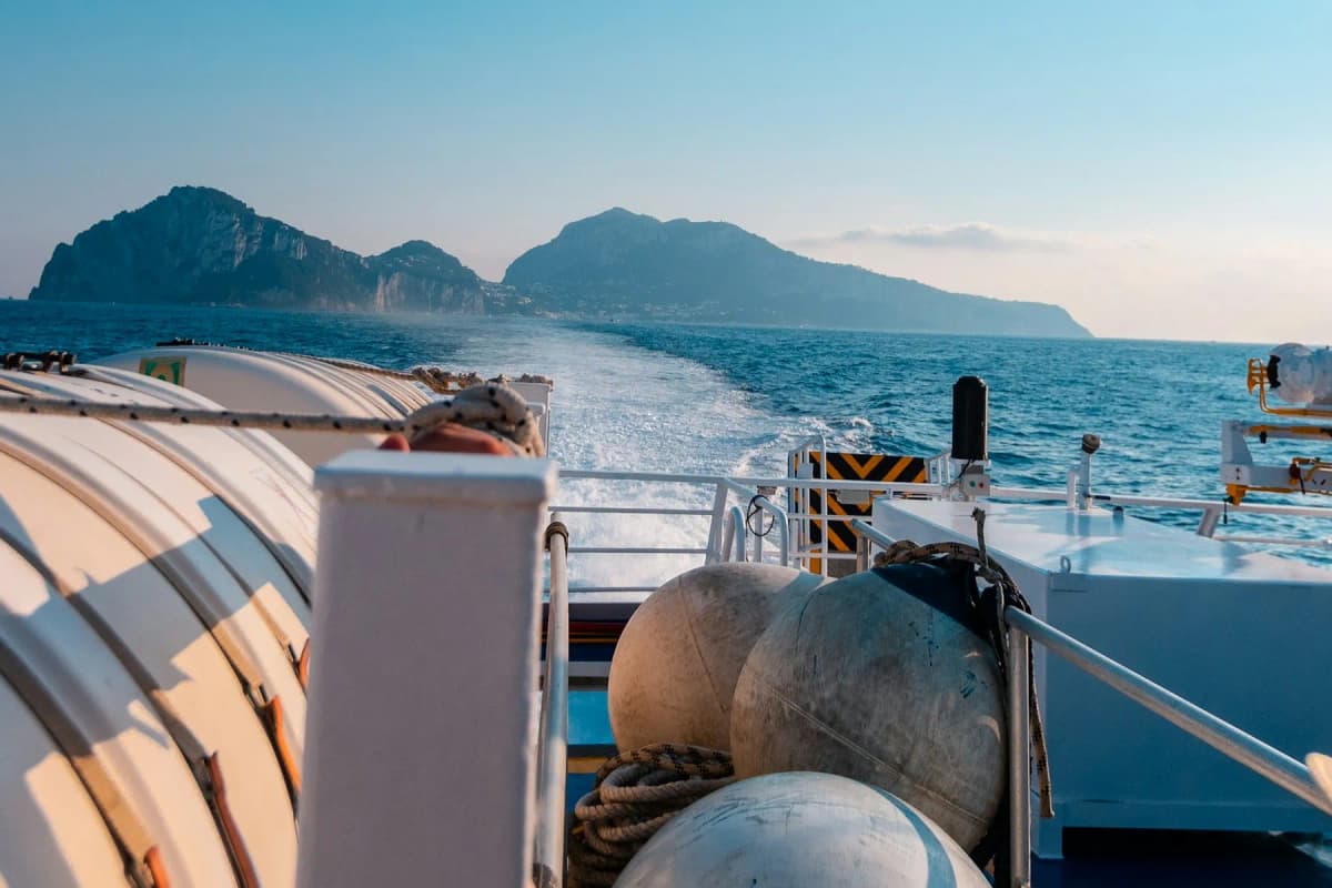 The view from the stern of a ferry across the sea towards rocky islands