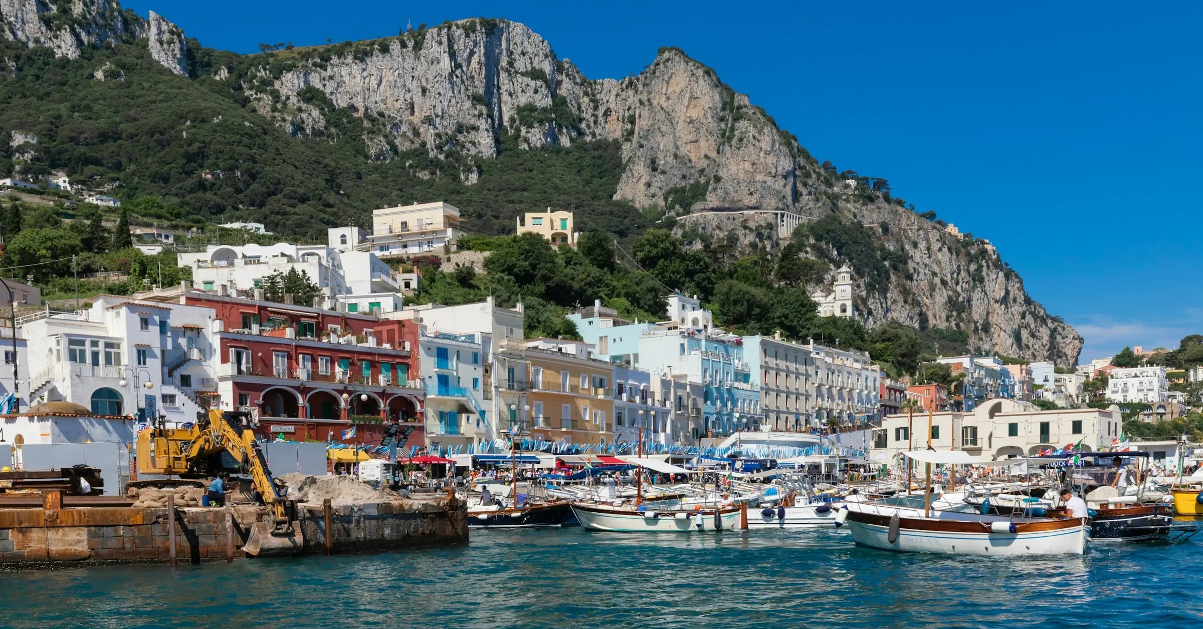 Naples to Capri: boats in Marina Grande harbour on Capri with white houses and limestone cliffs behind