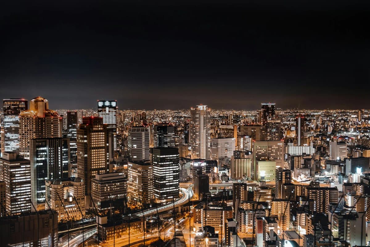 The Osaka city skyline at night seen from above, with lit towers and streets