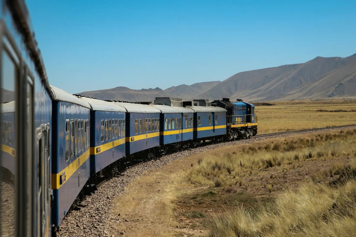 A blue train crossing the high grasslands of the Peruvian Andes