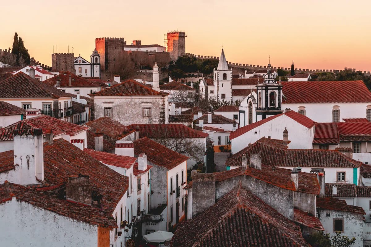 The castle and whitewashed houses of the walled village of Óbidos at sunset