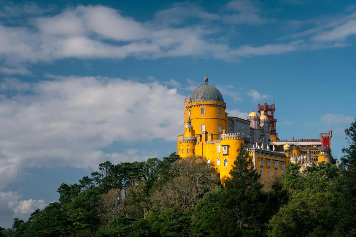 The yellow and red Pena Palace on a forested hilltop above Sintra