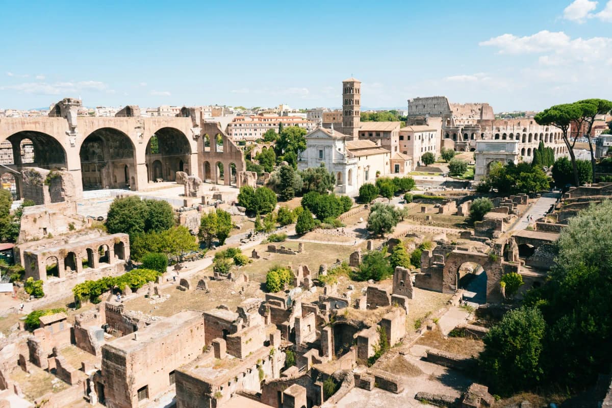 The ruins of the Roman Forum seen from above with the Colosseum in the distance