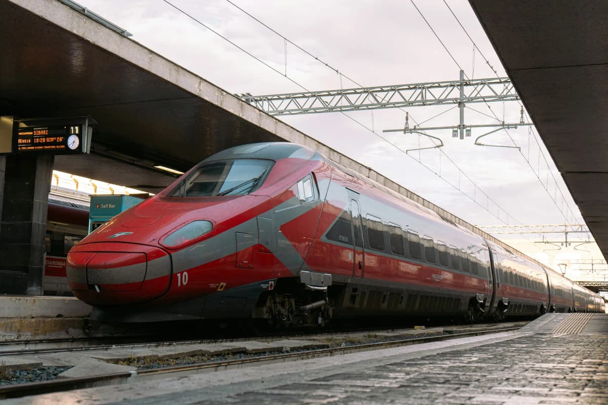 A red Frecciarossa high-speed train waiting at a station platform in Italy