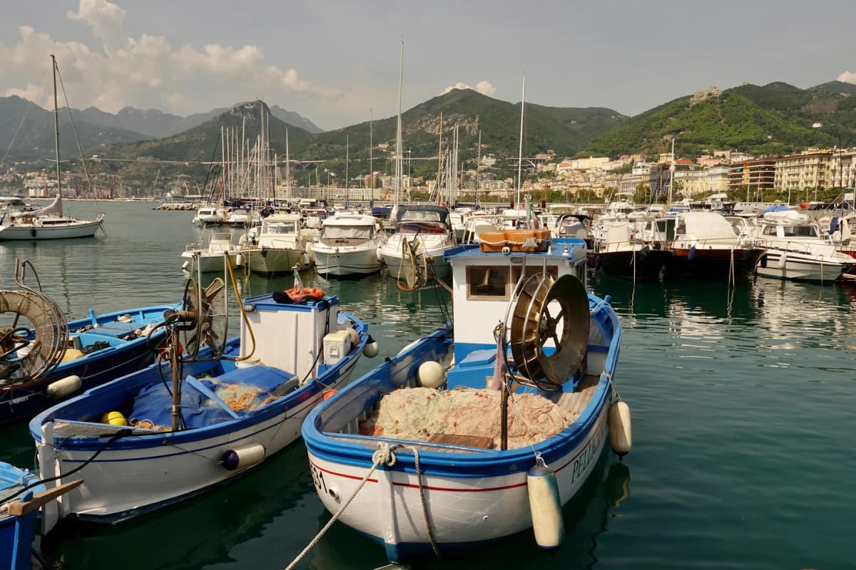 Fishing boats moored in the port of Salerno with the city and hills behind
