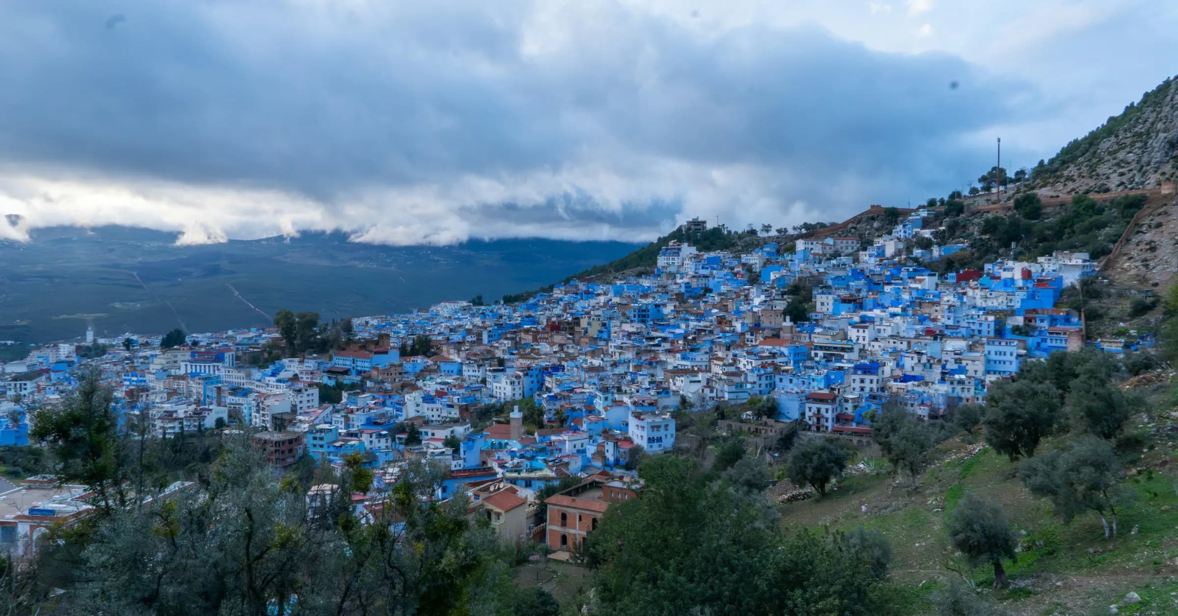 Tangier to Chefchaouen: the blue houses of Chefchaouen on a hillside in the Rif mountains under a cloudy sky
