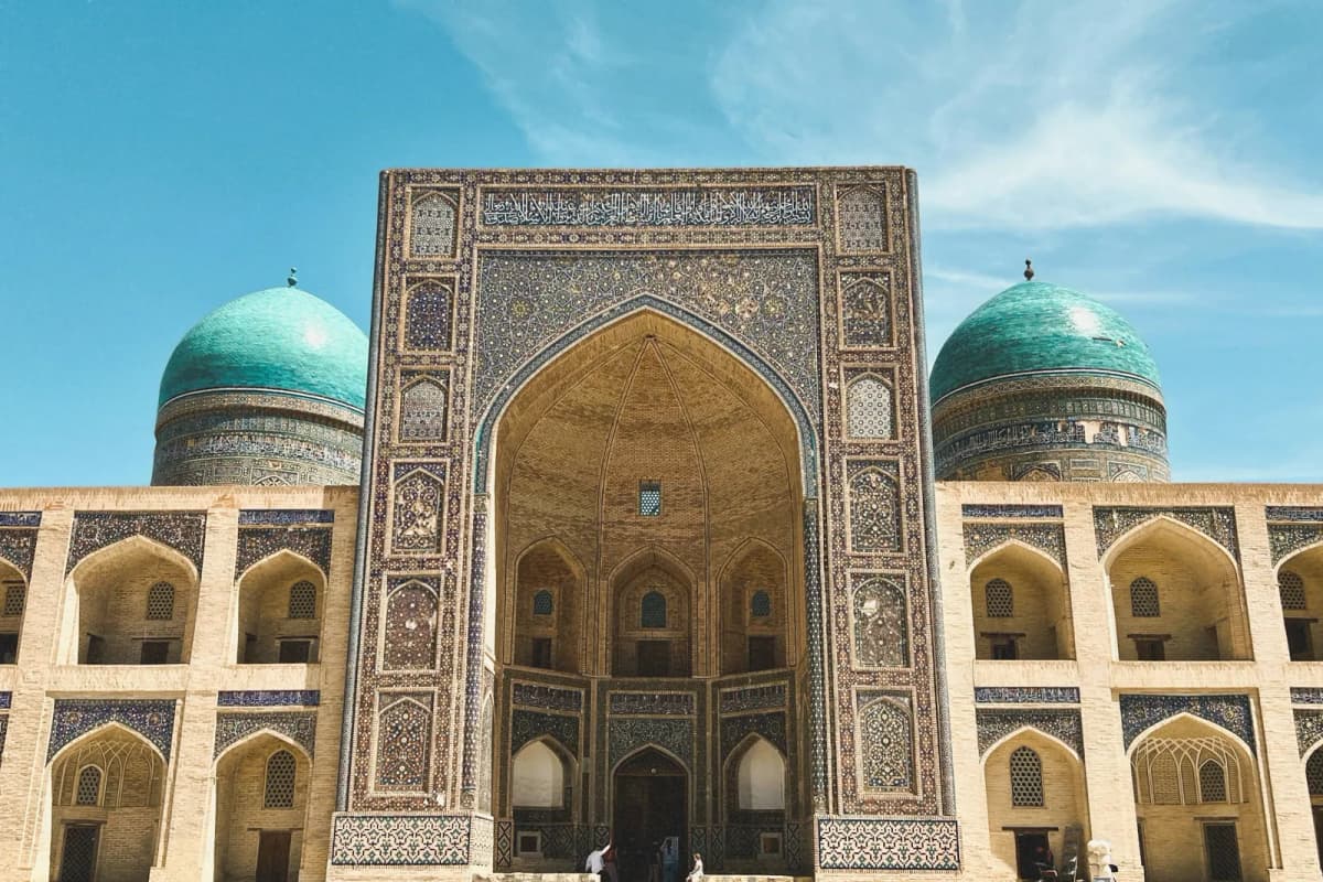 Things to do in Bukhara: the tiled portal and twin turquoise domes of the Mir-i-Arab Madrasah on a sunny day
