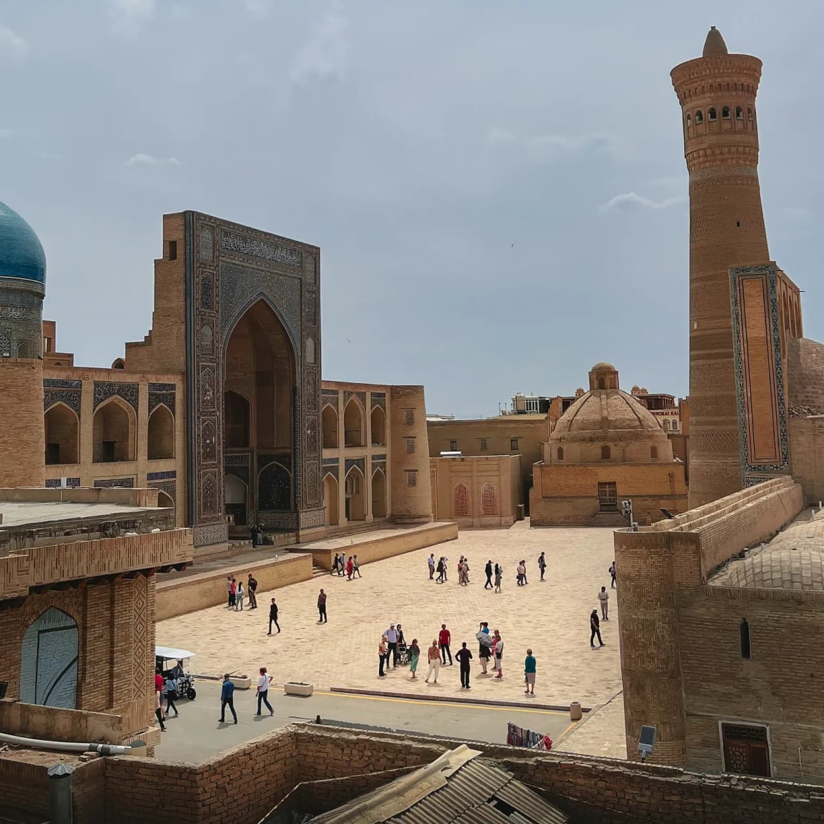 Things to do in Bukhara: the Kalyan Minaret rising above the courtyard of the Kalyan Mosque, with visitors crossing the square below