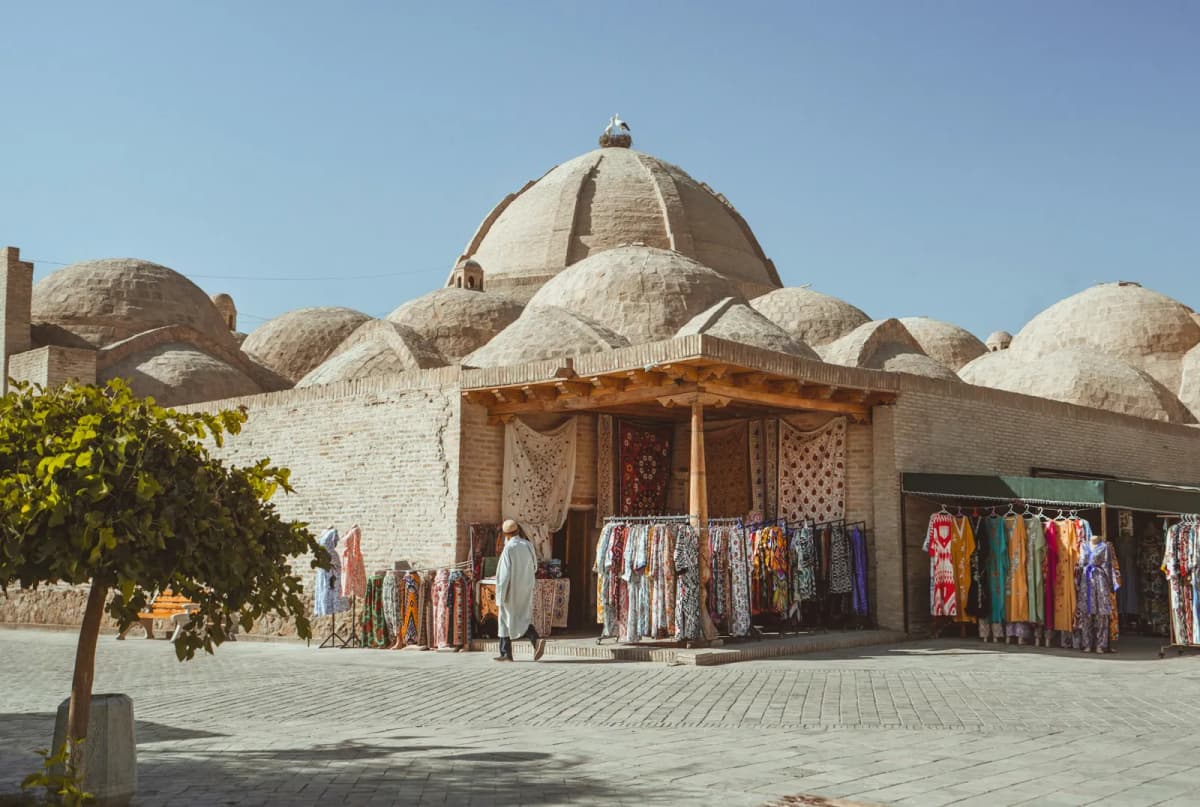 Things to do in Bukhara: one of the brick trading domes of the old city, with colourful fabrics hanging outside a stall