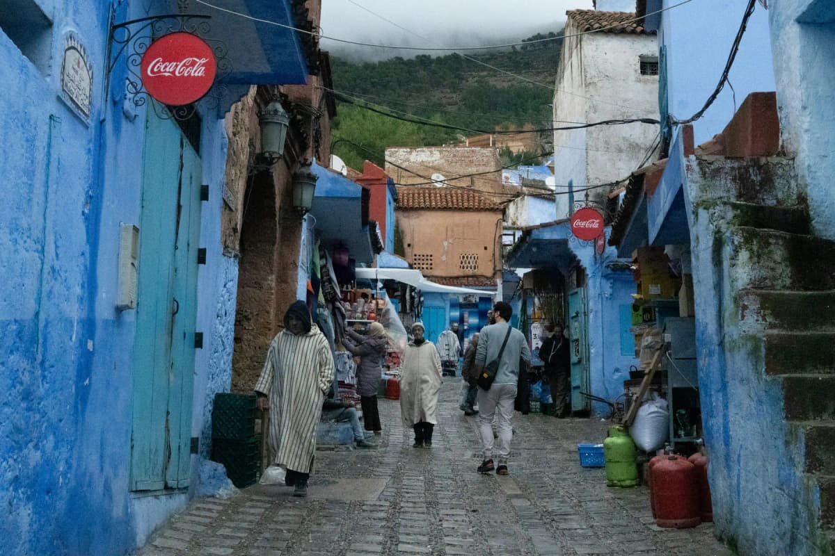 A blue street in the Chefchaouen medina with small shops and cafés