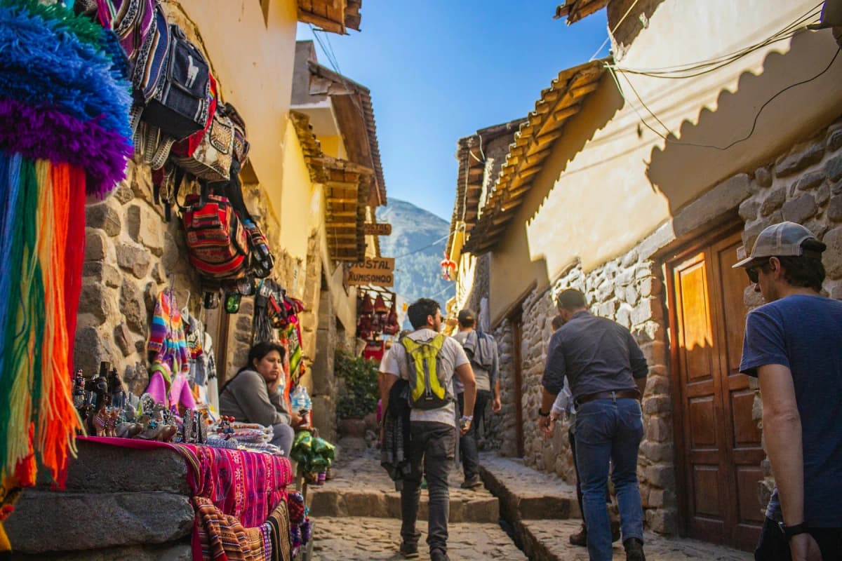 A steep, narrow street in Cusco's old town lined with textile stalls and whitewashed walls