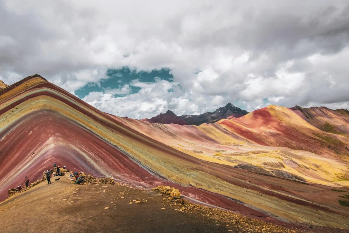The striped red, yellow and green slopes of Rainbow Mountain under a cloudy sky