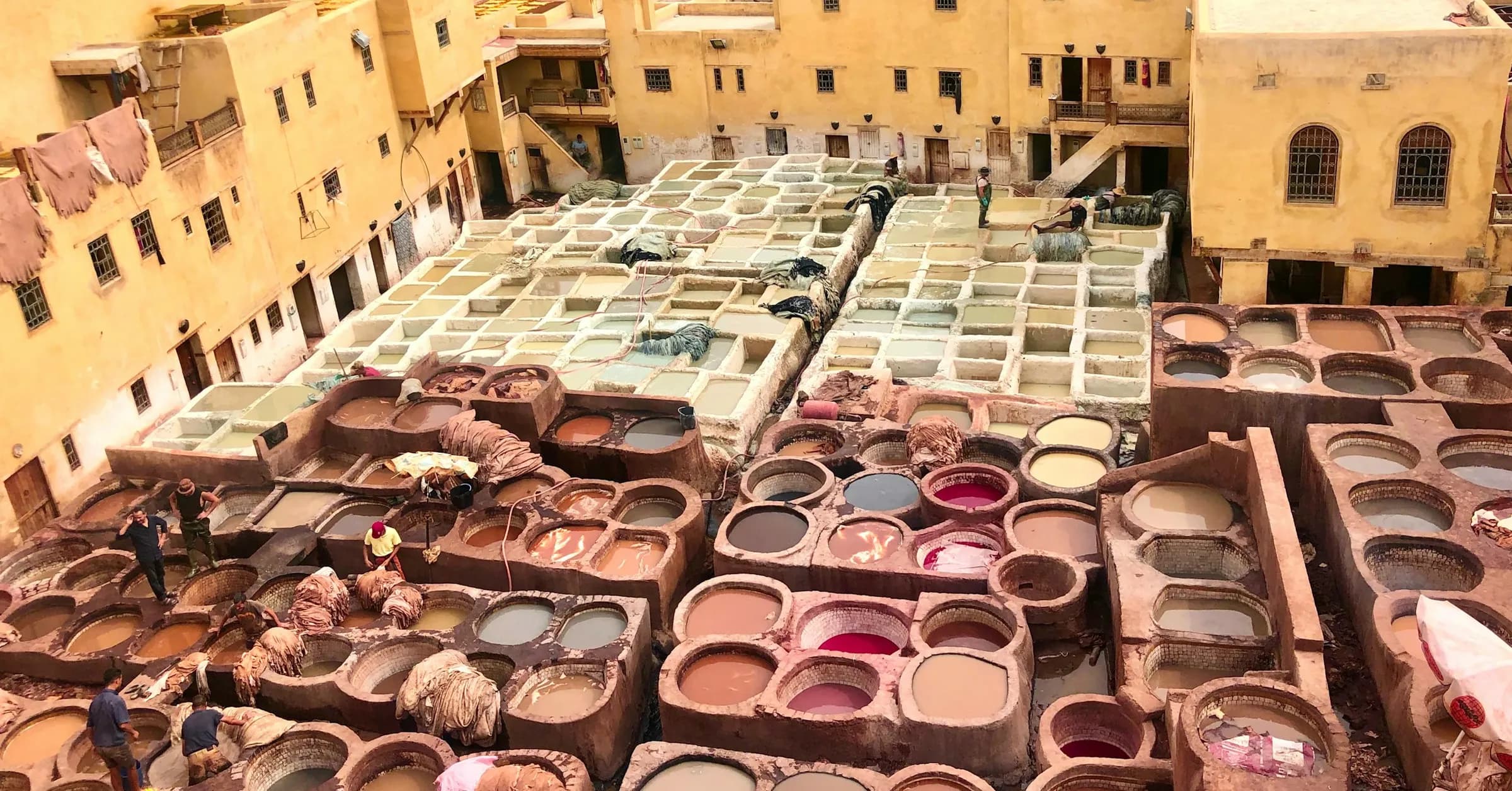 Things to do in Fes: the stone dye vats of the Chouara tannery surrounded by the ochre houses of the medina