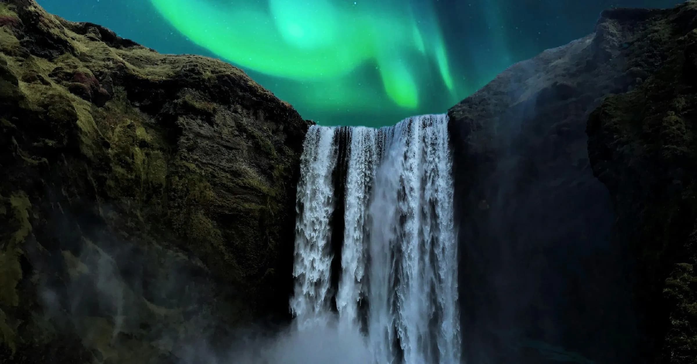 Skógafoss waterfall at night under green northern lights, with a small group of people standing at its base