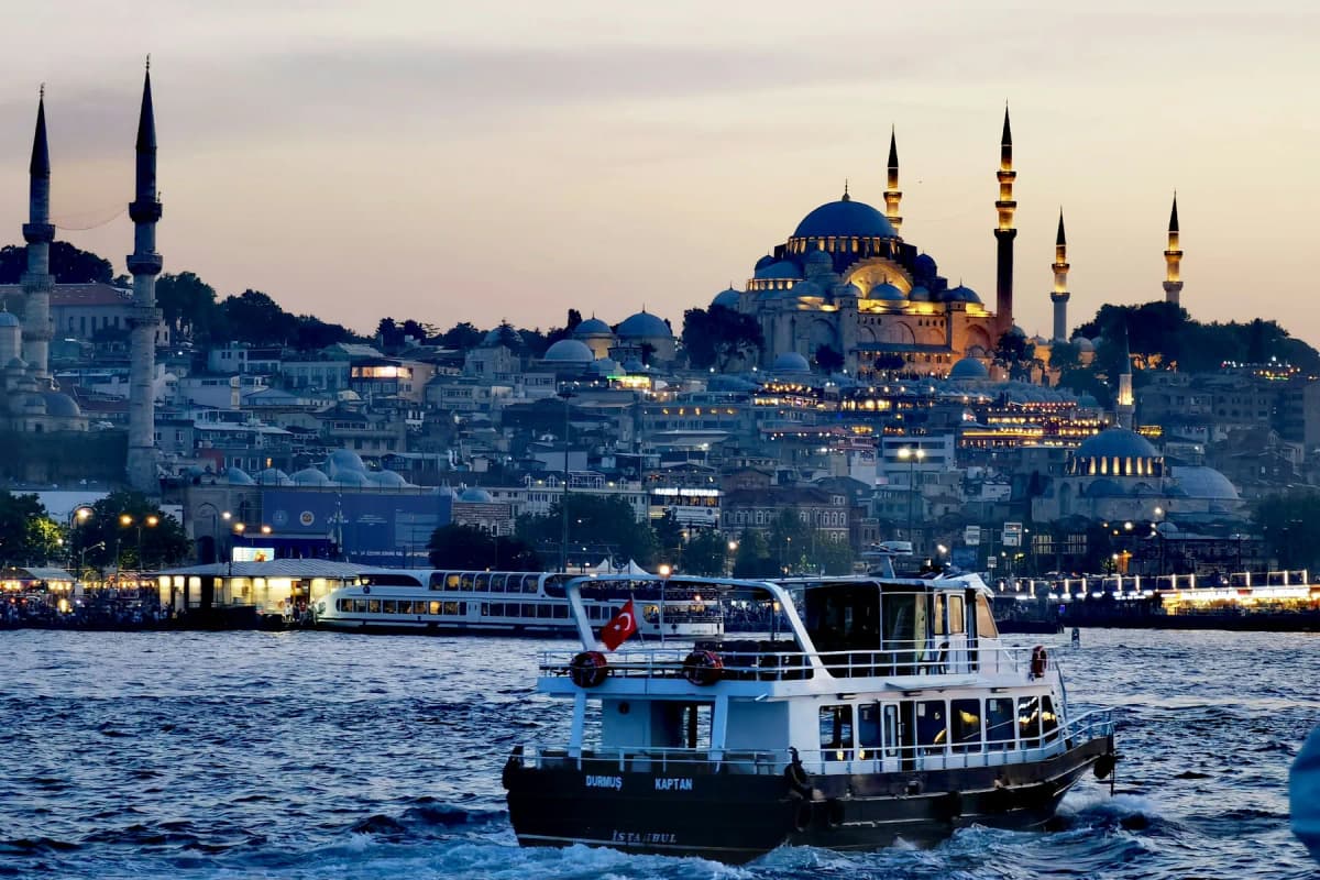 A ferry on the Bosphorus at dusk, with the Süleymaniye Mosque lit up on the skyline
