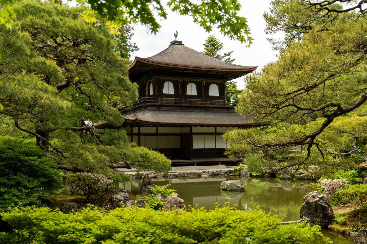 The wooden Silver Pavilion of Ginkaku-ji surrounded by pine trees and a pond in Kyoto