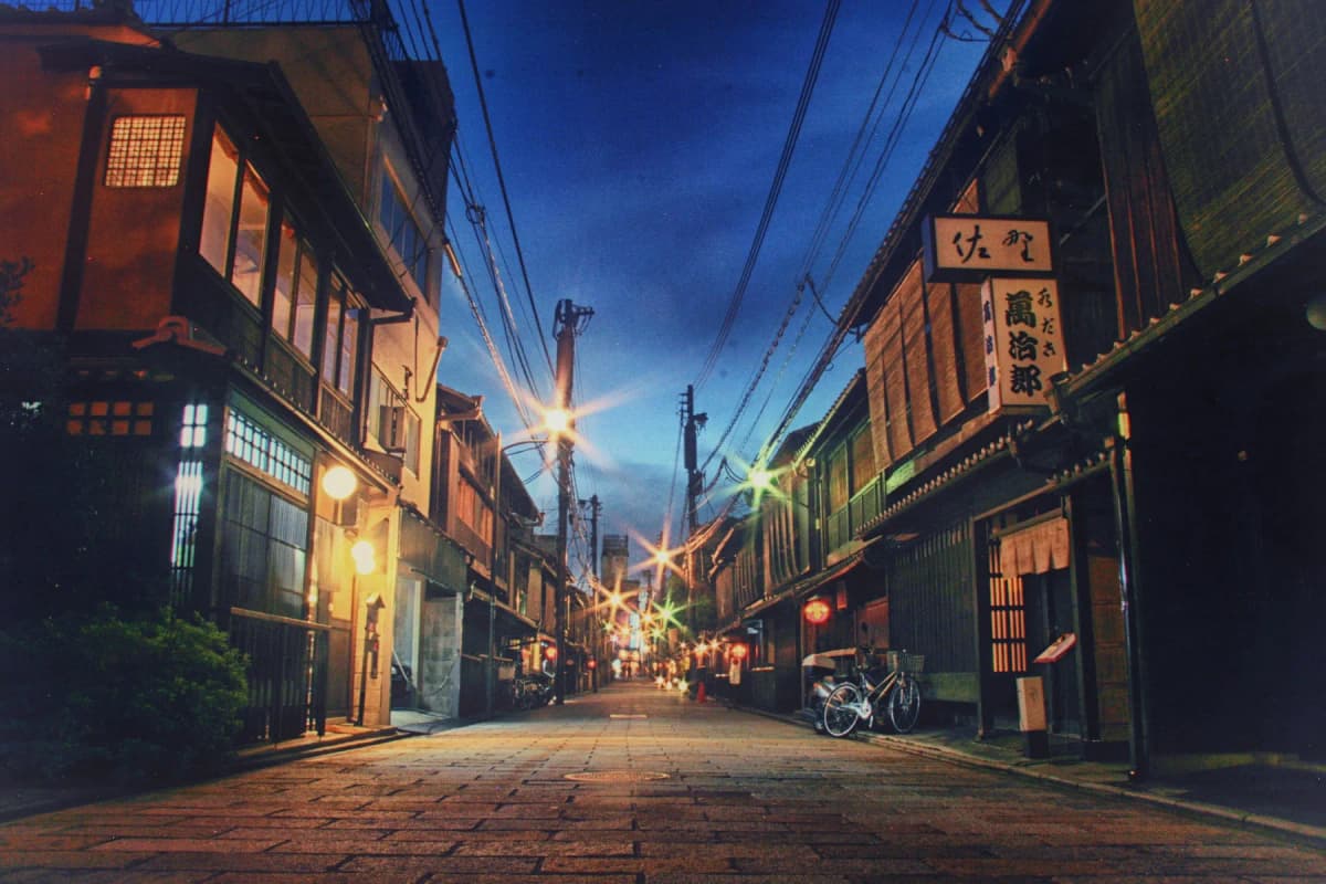 A quiet street of traditional wooden townhouses in Kyoto's Gion district at dusk